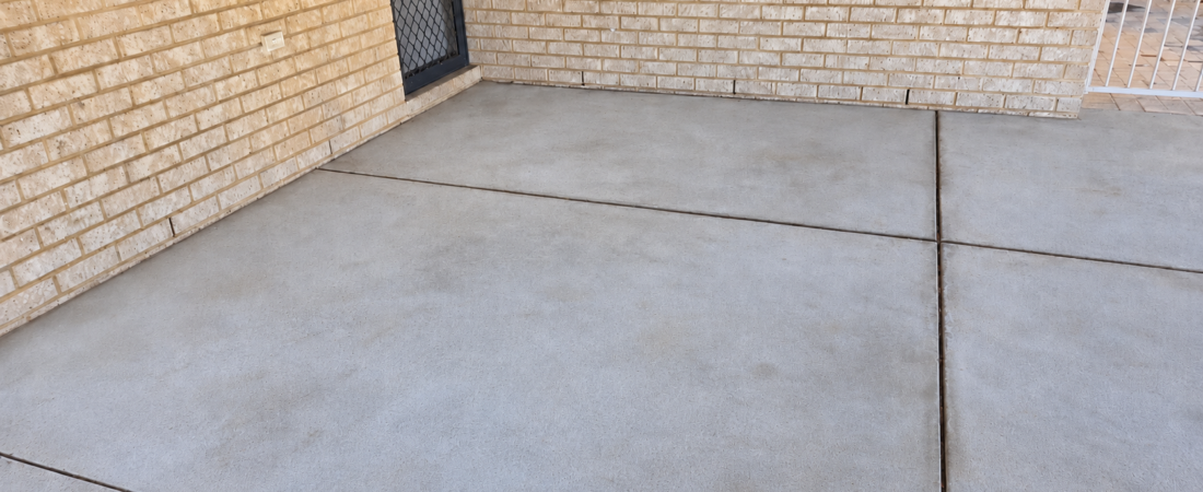 Concrete garage floor after pressure cleaning, showing a much cleaner surface with most oil stains and dirt removed