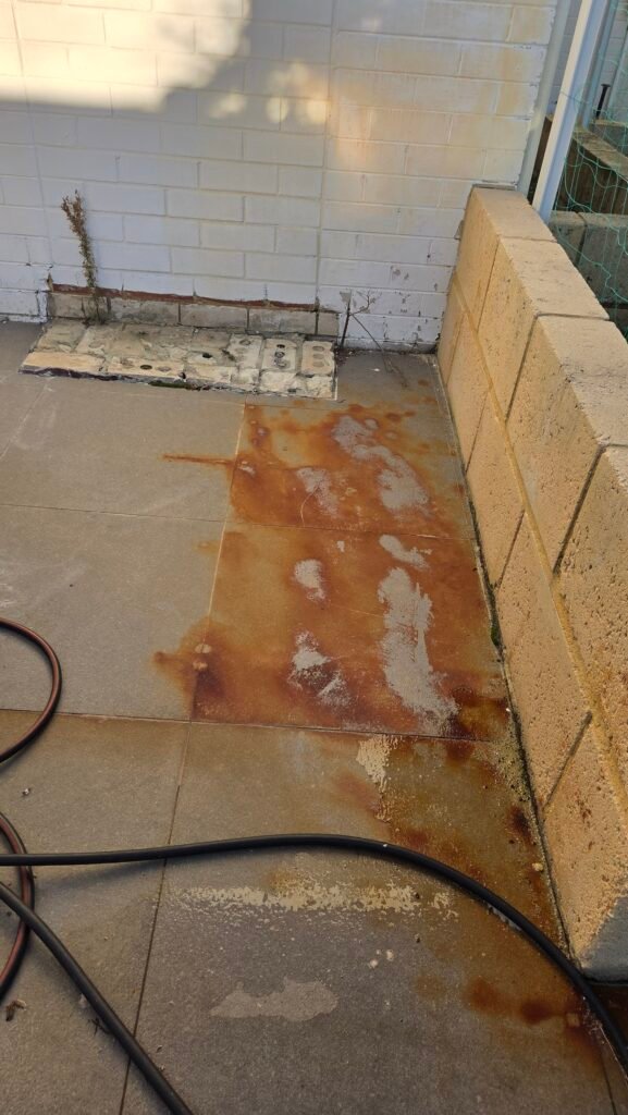 Outdoor patio tiles with heavy orange rust staining before cleaning in Perth